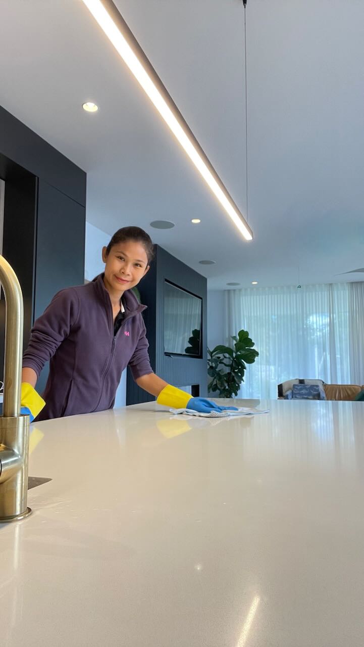 Aom, the main team member of THAIDY Cleaning Services, wiping a spotless stone benchtop with dedication and professionalism